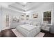 Comfortable main bedroom with tray ceiling, ensuite bath, and light-filled windows at 7025 Bavarian Wood Pl, Buford, GA 30518