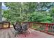 View of outdoor deck with weathered wood, dark metal patio set, and a lovely surrounding tree canopy at 1882 Flowering Dr, Grayson, GA 30017