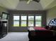 Bedroom featuring a lake view through large windows, tray ceiling, and dark wood dresser at 2657 Gray Mill Way, Loganville, GA 30052