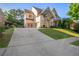 Stately stone and brick home featuring a circular driveway and well-manicured landscaping at 2604 Heltonwood Ct, Buford, GA 30519
