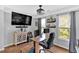 This home office includes a modern desk, shelving, a TV, and natural light from a nearby window at 1274 Cotton Gin Dr, Powder Springs, GA 30127