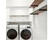 Bright laundry room with modern white washer and dryer and wooden shelving at 1815 Coventry Rd, Decatur, GA 30030