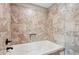 Relaxing bathroom featuring a soaking tub with jacuzzi jets and beige tile surround at 615 Henderson Mill Rd, Covington, GA 30014