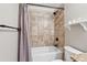 Bathroom featuring white toilet and tub with shower, granite countertop, and neutral tiling at 615 Henderson Mill Rd, Covington, GA 30014