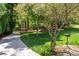 Exterior shot with well manicured lawn and gardens, a long driveway, and surrounding mature trees at 148 Bramble Oak Dr, Woodstock, GA 30188