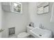 Cozy bathroom with a toilet, sink, mirror, white-painted paneled walls, and natural light from a window at 1544 Brewer Sw Blvd, Atlanta, GA 30310
