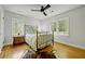Bright bedroom featuring a ceiling fan, hardwood floors, three windows, and an antique-style bed at 1544 Brewer Sw Blvd, Atlanta, GA 30310