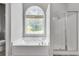 Bright bathroom showcasing a garden tub with arched window and glass door shower at 543 Serene Waters Trl, Jonesboro, GA 30236
