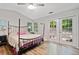 This primary bedroom boasts a four-poster bed, ceiling fan, wood floors, and glass doors to the backyard at 10650 Colony Glen Dr, Johns Creek, GA 30022