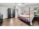 This primary bedroom features a four-poster bed, wood floors, ceiling fan, and natural light at 10650 Colony Glen Dr, Johns Creek, GA 30022