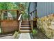 Wooden stairs leading to the home with stone accents, metal railings, and lush greenery surrounding at 945 Tiber Cir, Alpharetta, GA 30022