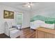 This cozy room features a wood floor, a ceiling fan, and a white crib next to a wall painted with green mountains at 1605 Saddlecreek Rd, Auburn, GA 30011