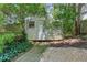 Exterior view of storage shed with trees, stone and concrete path in backyard at 1605 Saddlecreek Rd, Auburn, GA 30011