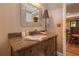 Elegant bathroom featuring a granite countertop, decorative mirror, and dark wood cabinetry at 1668 Macy Ln, Lawrenceville, GA 30043