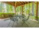 Relaxing covered patio featuring brick pavers, a dining set, and a bench swing surrounded by lush greenery at 1668 Macy Ln, Lawrenceville, GA 30043