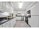 A well-lit kitchen features white cabinets, black countertops, stainless steel appliances, and gray wood flooring at 705 Beaufort Cir, Duluth, GA 30096