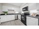 A lovely kitchen features white cabinets, black appliances, stainless steel dishwasher, and gray wood flooring at 705 Beaufort Cir, Duluth, GA 30096