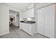 A practical kitchenette with white cabinets, black countertops, gray wood flooring, and a closet at 705 Beaufort Cir, Duluth, GA 30096
