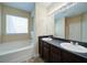 Bathroom featuring double sinks, dark wood cabinets, separate tub, and a large mirror at 1575 Parkside Village Dr, Cumming, GA 30040