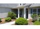 Home's covered front porch has trimmed bushes and a sidewalk leading to the front door at 1575 Parkside Village Dr, Cumming, GA 30040