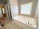 Relaxing bathroom with a large soaking tub, tiled surround, and natural light from a glass block window at 8967 Midlothian Ct, Winston, GA 30187