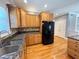 Kitchen with wooden cabinets, stainless steel sink, black appliances, and stone countertops at 8967 Midlothian Ct, Winston, GA 30187