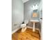 Powder room with pedestal sink, decorative mirror and lighting, and hardwood flooring at 8967 Midlothian Ct, Winston, GA 30187