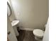 Powder room features pedestal sink, toilet, and dark wood-look flooring at 201 Jonquil Spring Rd, Woodstock, GA 30188