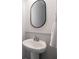 Elegant bathroom with pedestal sink, oval mirror, and white wainscoting adding a touch of sophistication at 5440 Wheeler Ridge Rd, Auburn, GA 30011