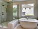 Luxury bathroom features a glass shower, soaking tub, and a large window for natural light at 3065 Reserve Ct Sw, Conyers, GA 30094