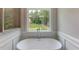 Close up view of bathtub in bathroom with glass shower and beautiful window view of the lush backyard at 3292 Mill Forest Dr, Conyers, GA 30094
