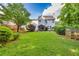 Wide backyard showcasing a covered patio area, lush lawn, and bordered by trees and wooden fencing at 4174 Chatham Crest Ln, Buford, GA 30518