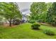 Wide shot of a well-kept backyard with a large grassy area, mature trees, and a partially covered patio at 4174 Chatham Crest Ln, Buford, GA 30518