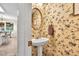 Charming half bathroom with pedestal sink, floral wallpaper, and decorative mirror at 4174 Chatham Crest Ln, Buford, GA 30518