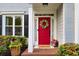 Charming red front door with a wreath, complemented by lush landscaping and a welcoming entrance at 4174 Chatham Crest Ln, Buford, GA 30518