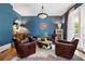 Stylish living room boasts a bright blue accent wall, hardwood floors, and an arrangement of four leather chairs at 4530 Upland Court, Cumming, GA 30040