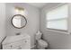 Cozy bathroom featuring a modern vanity, toilet, round mirror, and window at 5040 Meadow Lane Ne, Marietta, GA 30068