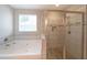 Bright bathroom featuring a soaking tub, a glass-enclosed shower with stone pebble flooring at 686 Stark St, Lawrenceville, GA 30046