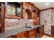 A close-up view of a custom bar featuring a sink, granite countertop, brick accents, and glassware storage at 414 Dogwood Way, Canton, GA 30114
