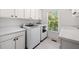 Well-lit laundry room with white cabinets, washer, dryer, and bright window at 414 Dogwood Way, Canton, GA 30114