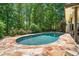 A backyard pool is surrounded by a stone patio and mature trees offering privacy at 414 Dogwood Way, Canton, GA 30114
