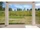 View from back patio with white pillars, overlooking grassy knoll and distant trees under a partly cloudy sky at 18 Dorothy Ln, Lawrenceville, GA 30046