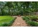 Landscaped backyard features a stone pathway leading to a fire pit and wooded area at 1920 Pilgrim Rd, Cumming, GA 30040
