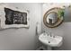 A half-bathroom with pedestal sink, round decorative mirror, and wood-look flooring at 1920 Pilgrim Rd, Cumming, GA 30040