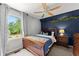 Bedroom with wood bed, dark blue accent wall, and window at 1920 Pilgrim Rd, Cumming, GA 30040