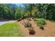 Landscaped area features red roses, green grass, wood mulch and variety of trees at 5465 Mountain Top Pl, Cumming, GA 30041