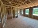 Unfinished living room exhibiting exposed framing, raw plywood flooring, and large windows for abundant natural light at 5371 Heron Bay Blvd, Locust Grove, GA 30248
