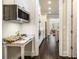 View into the kitchen from a hallway with white cabinets, stainless steel appliances and dark wood floors at 11375 Crestview Ter, Johns Creek, GA 30024