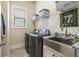 Well-lit laundry room featuring stainless steel sink and modern washer and dryer at 11375 Crestview Ter, Johns Creek, GA 30024