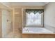 Luxurious bathroom with walk in shower and relaxing tub beneath a beautiful decorative window at 255 Beech Tree Holw, Sugar Hill, GA 30518
